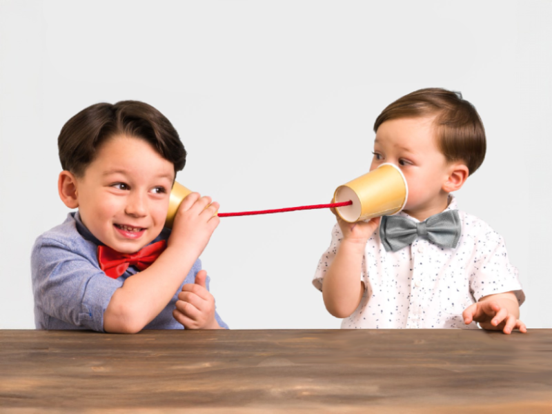 Zwei Kinder, die sich über ein Bechertelefon unterhalten